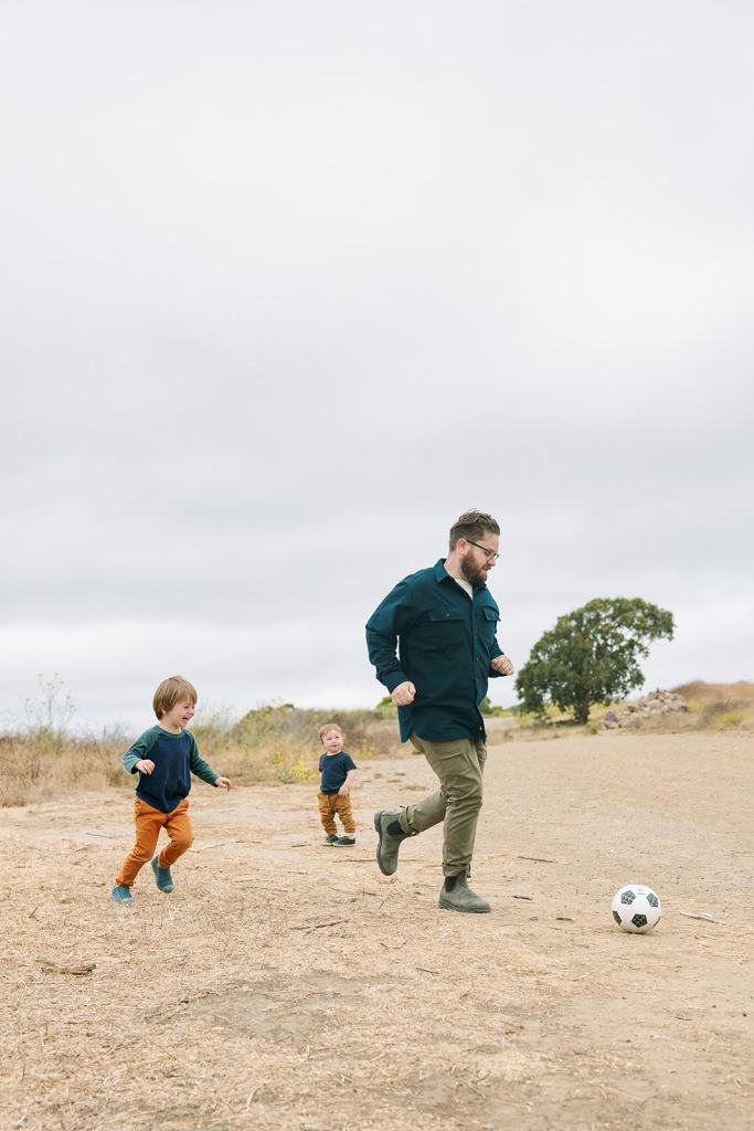 Dad and sons running on the beach at The Albany Bulb and playing soccer
