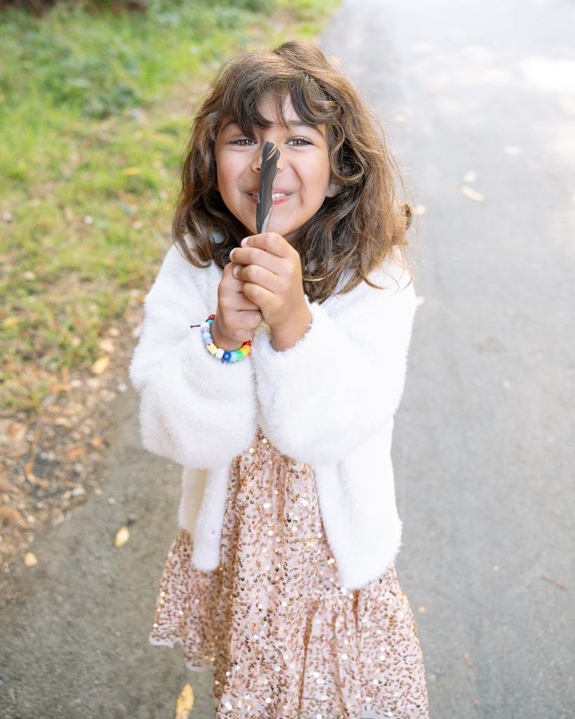 Little girl holding a bird feather and posing for picture