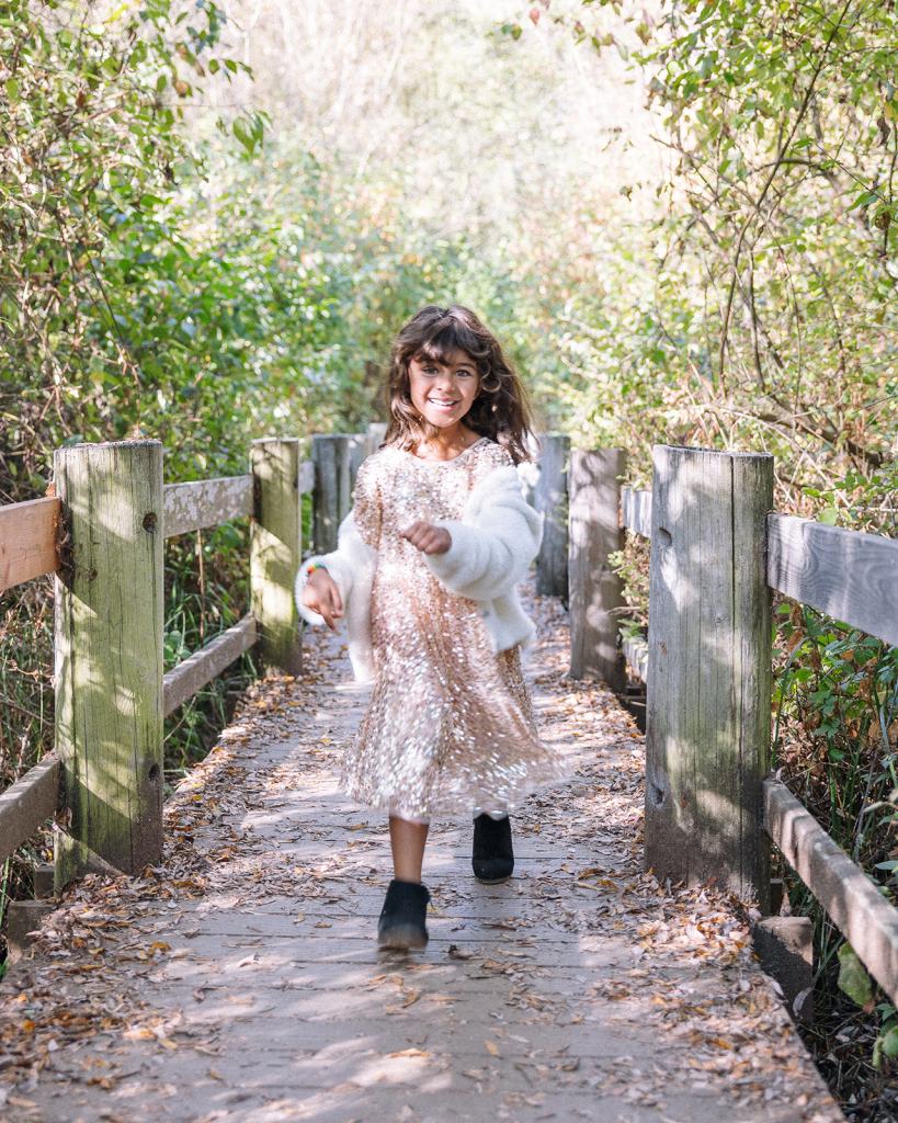 Little girl running along wooden park path during photoshoot