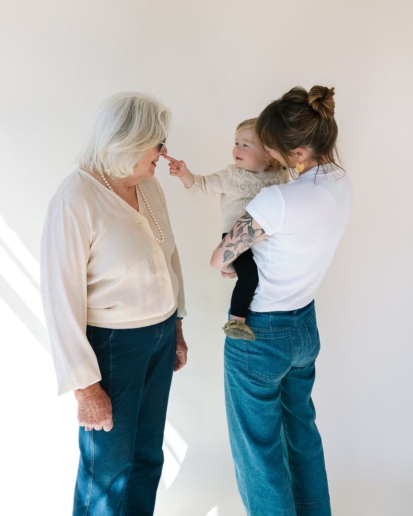 Grandmother, mother, and toddler son posing for studio motherhood photo session