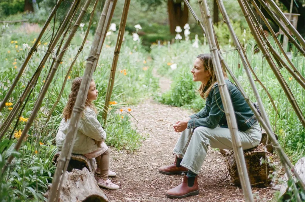 Mother and daughter sitting together under a stick teepee 