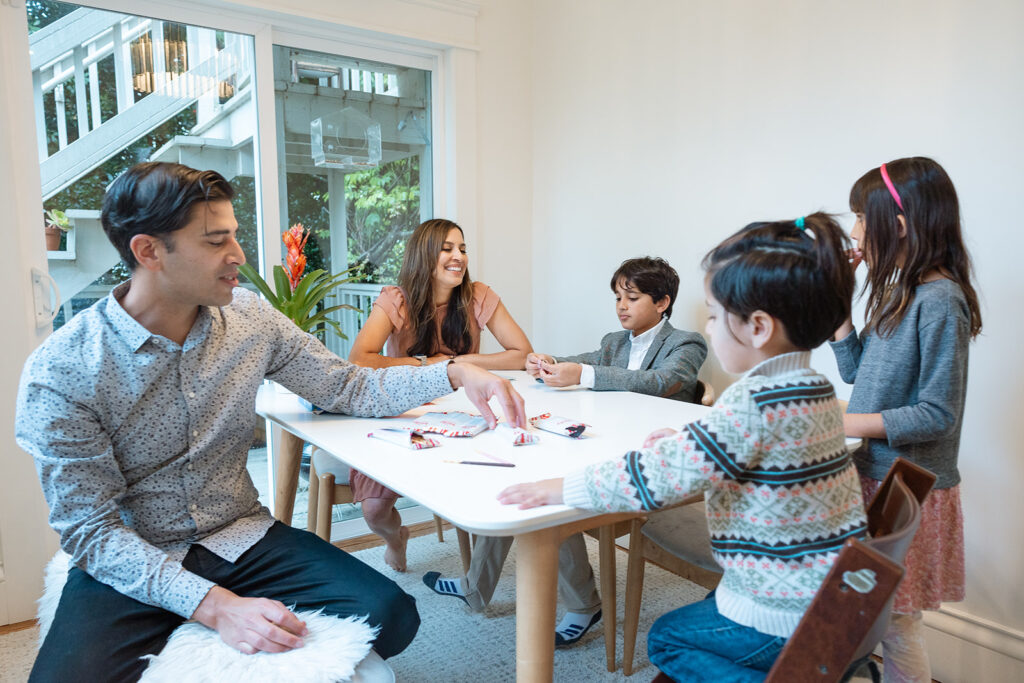 Family sitting at table together during their at home family photoshoot in San Francisco