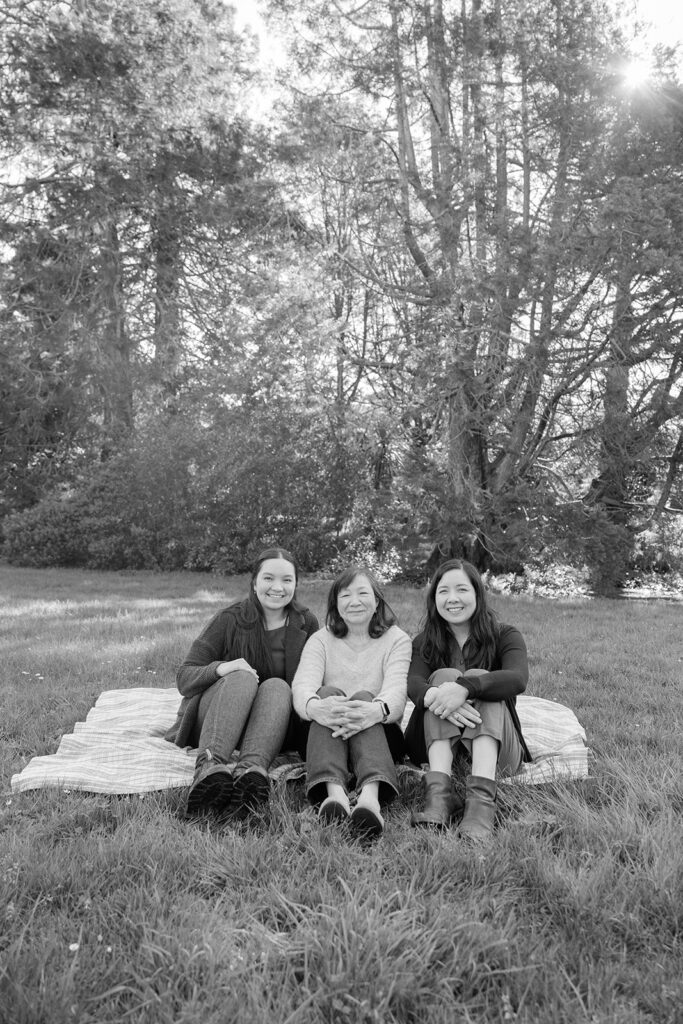 Mother and her two daughters sitting on a blanket in the grass