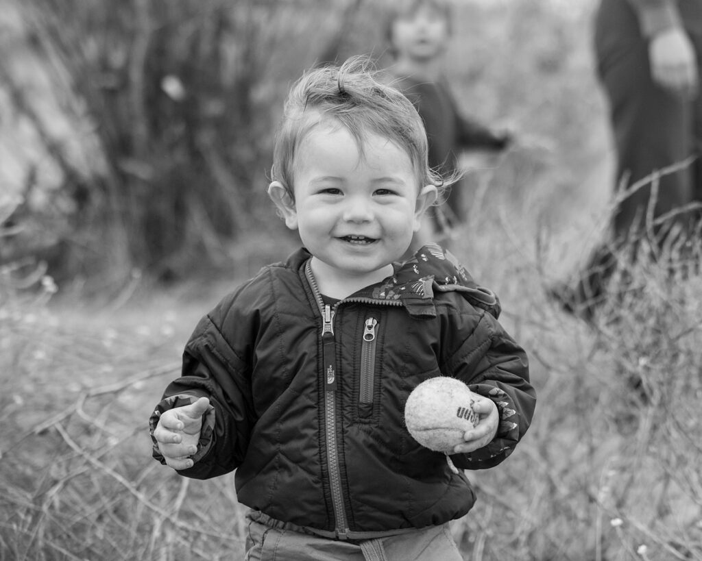 Black and white photo of a toddler boy holding a baseball