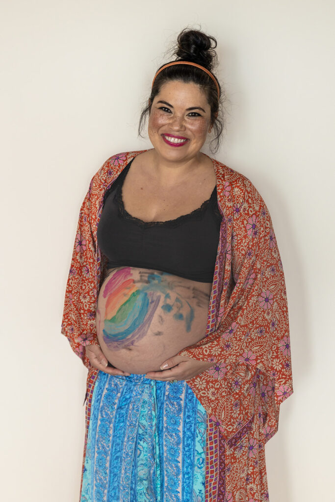 Pregnant woman posing for photos with a painted belly 