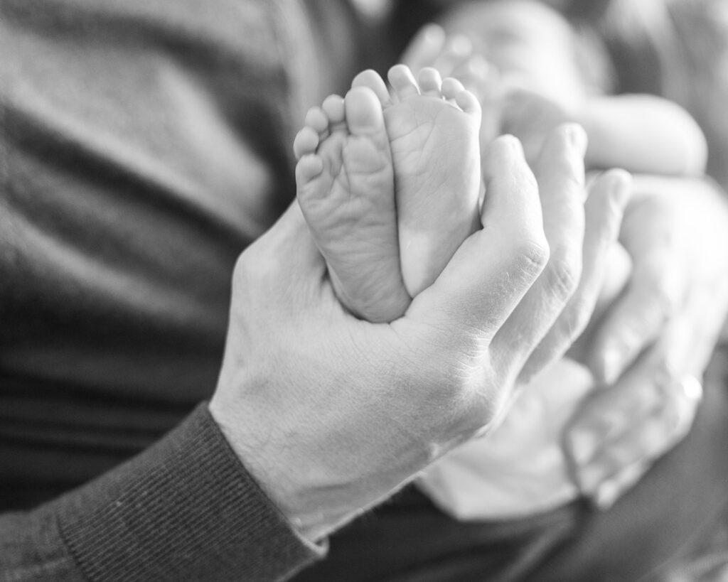 Father holding newborn babies feet