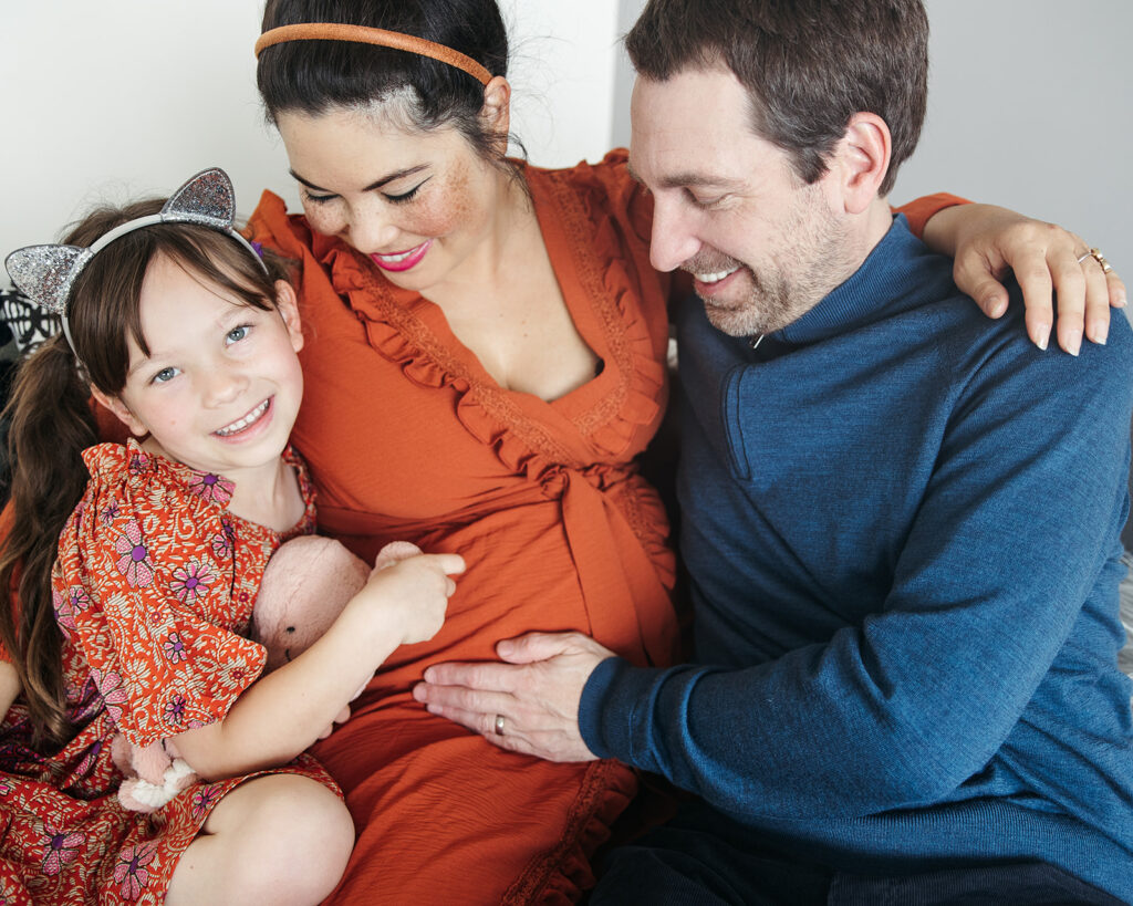 Daughter and father holding pregnant mothers belly during at home maternity photoshoot in the Bay Area