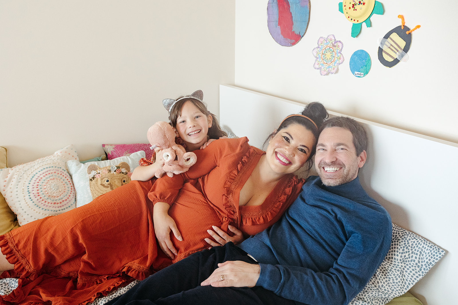 Family of three laying on a bed during an at home maternity photoshoot in the Bay Area