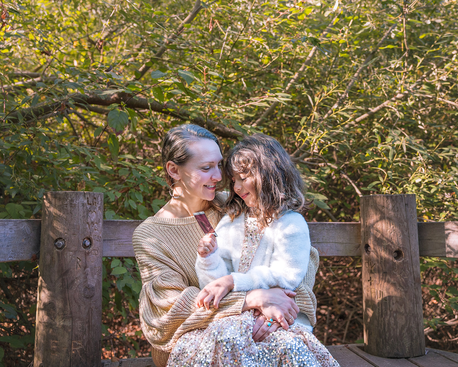 Mother and daughter sitting on a park bench during their mother and daughter photoshoot 
