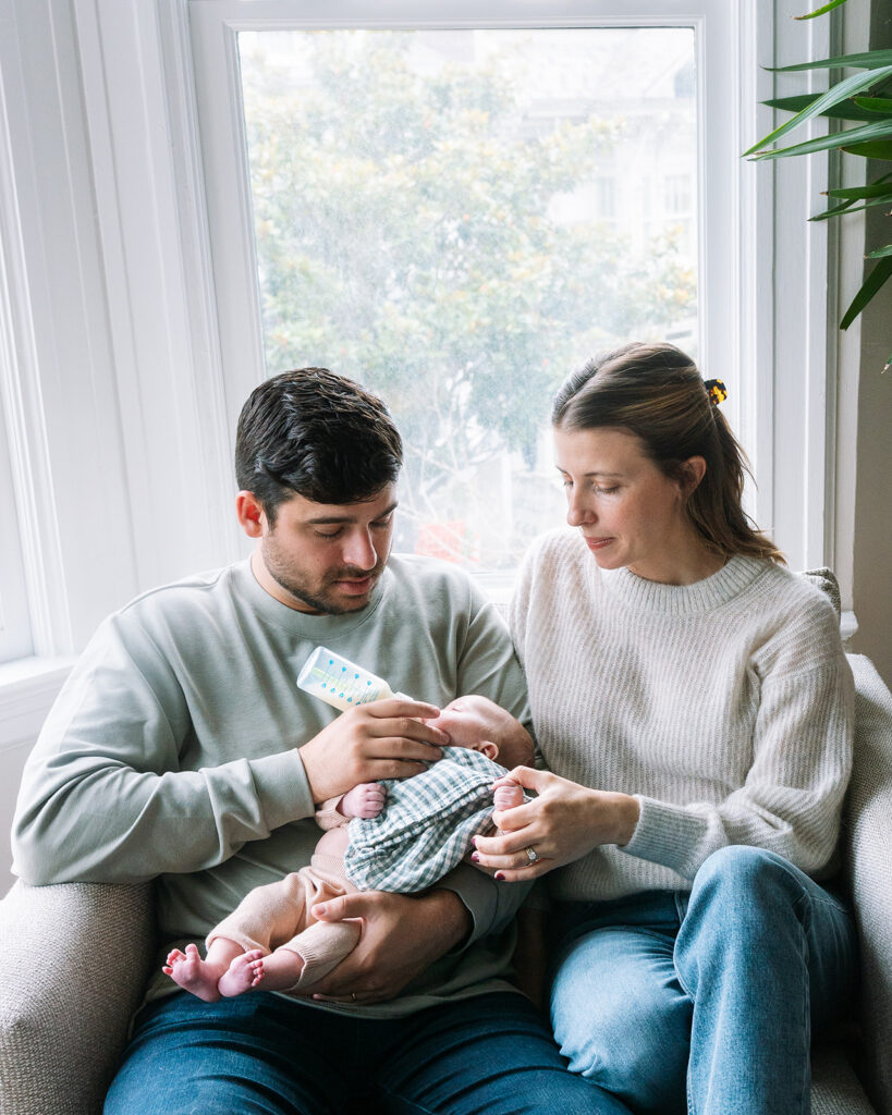 Mother and father feeding their newborn during their lifestyle at-home San Francisco newborn photoshoot