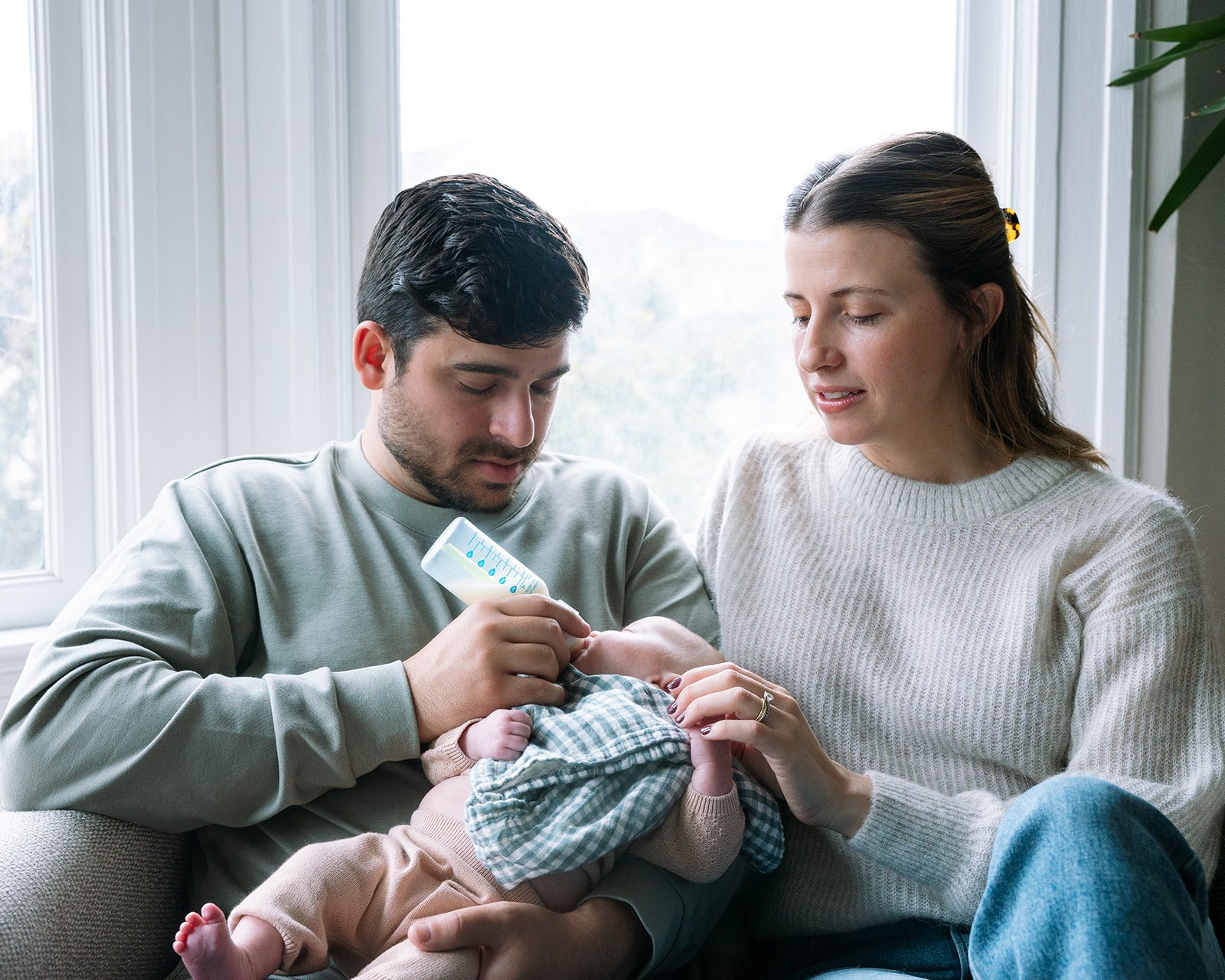 Mother and father feeding their newborn during their lifestyle at-home San Francisco newborn photoshoot