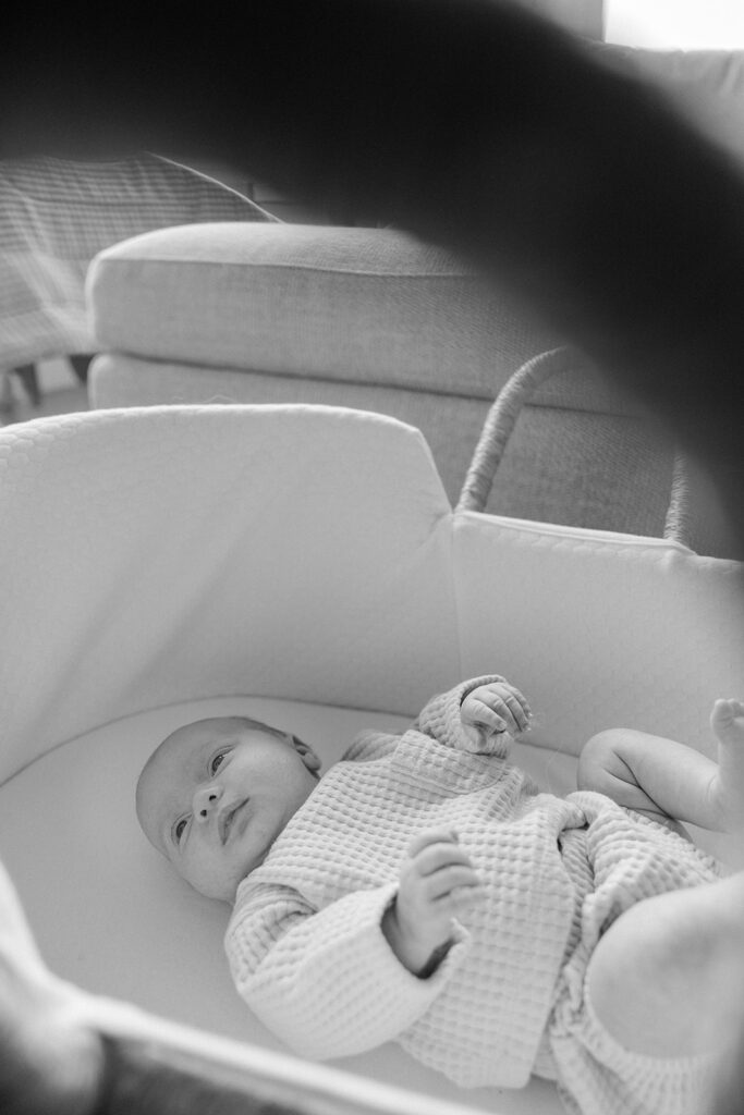 Black and white photo of a baby laying in the bassinet