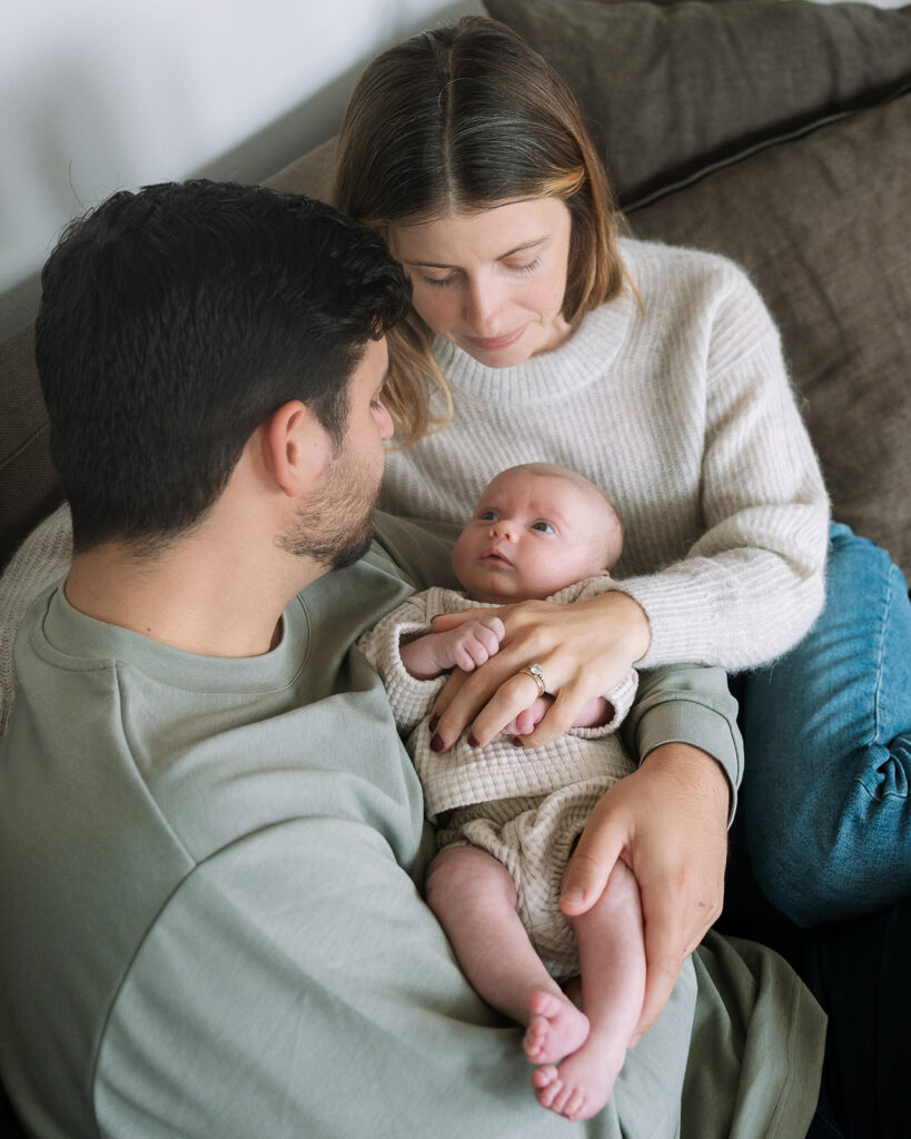 Mother and father cuddling with their newborn baby for their at-home San Francisco newborn photoshoot