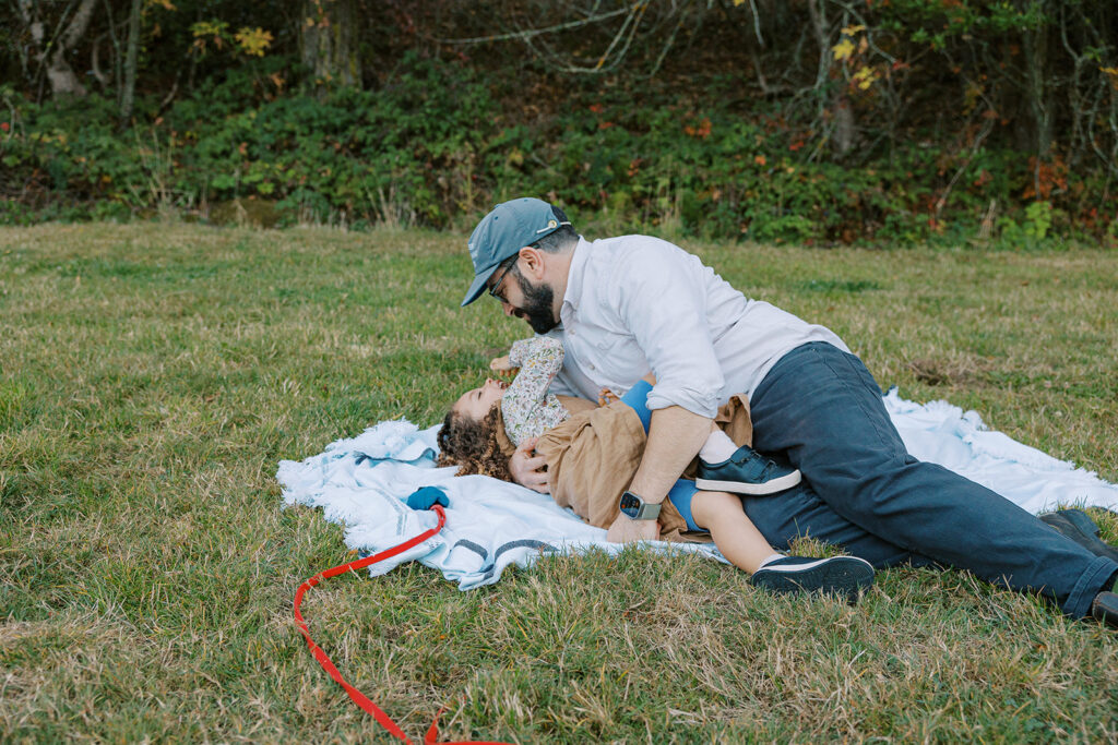 Father and daughter playing in the grass for their maternity & family pictures