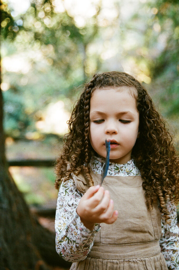 Little girl looking at a feather on 35mm film