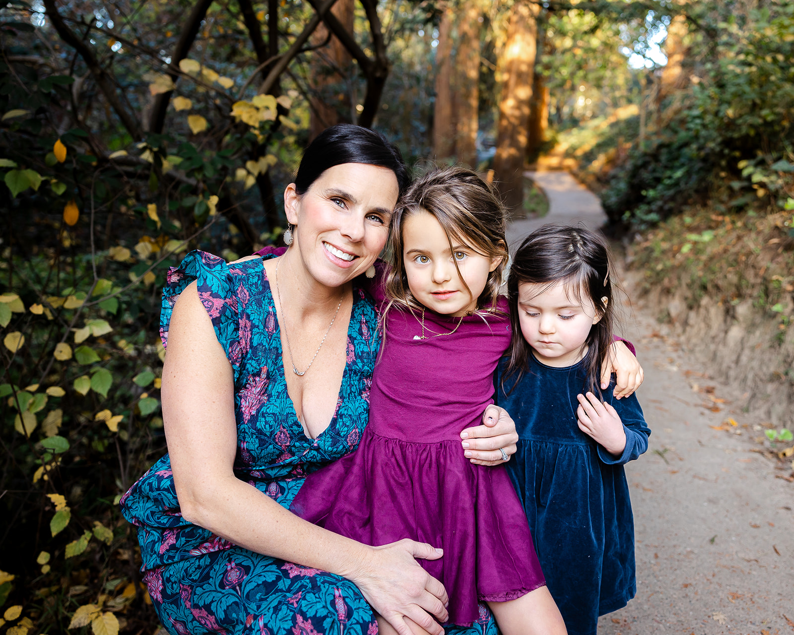 Mother posing for photo with her two young daughters for their fall family photos at Piedmont Park in the East Bay of California