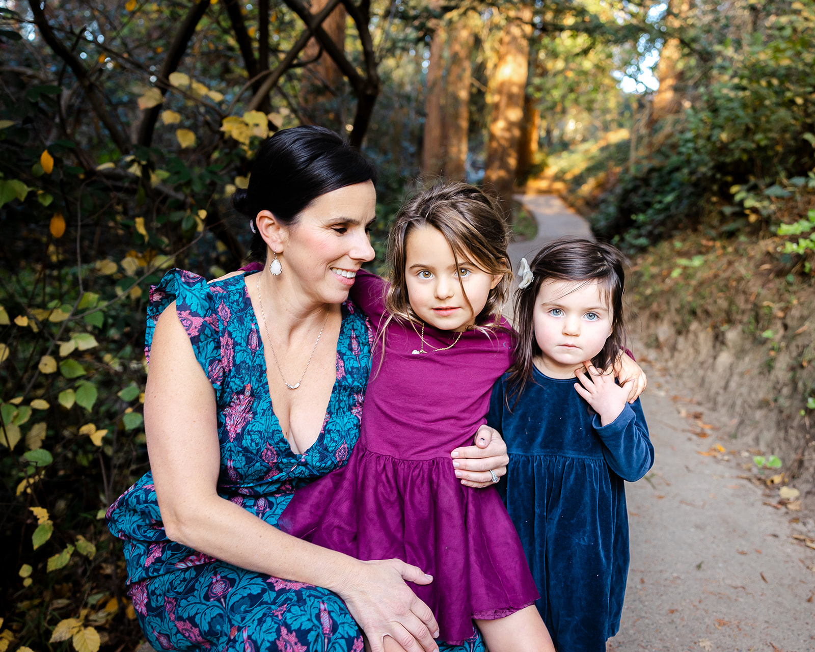 Mother posing for photo with her two young daughters for their fall family photos at Piedmont Park in the East Bay of California