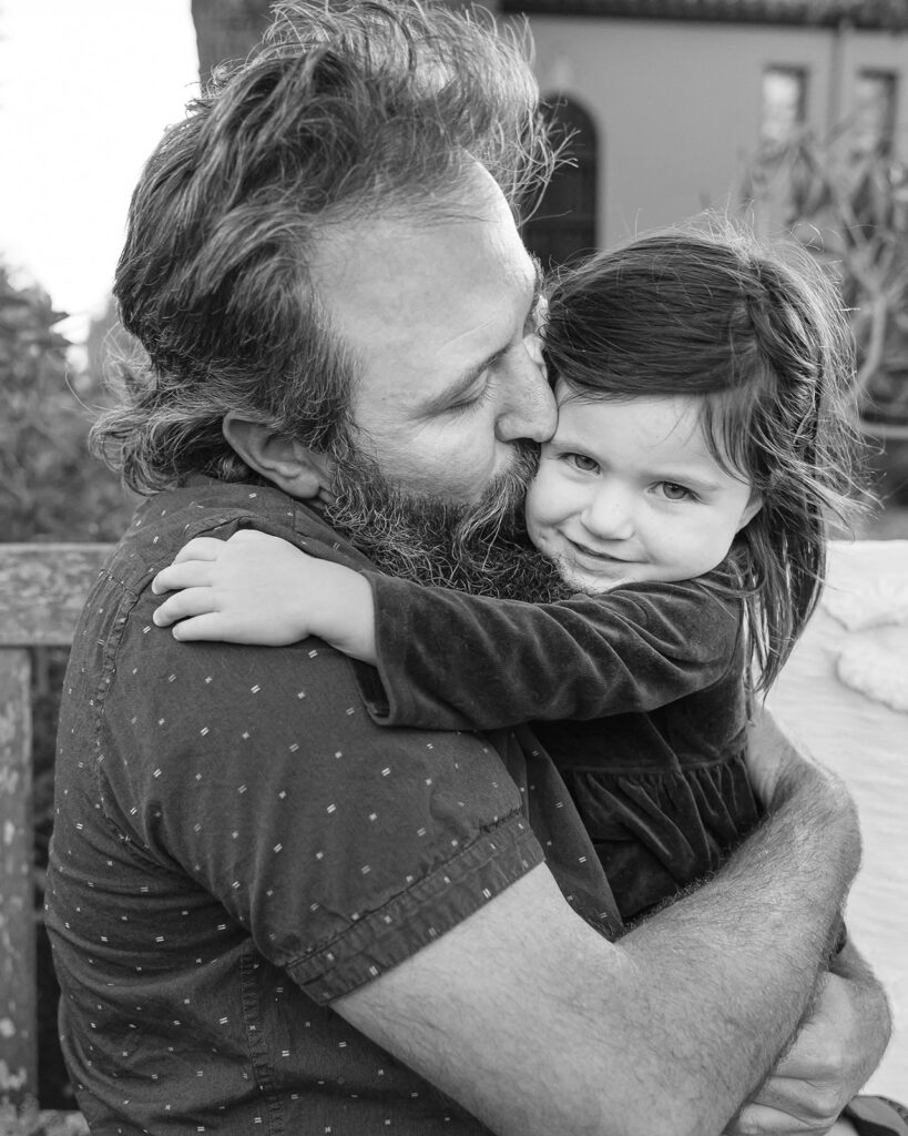 Black and white photo of a father kissing his toddler daughter