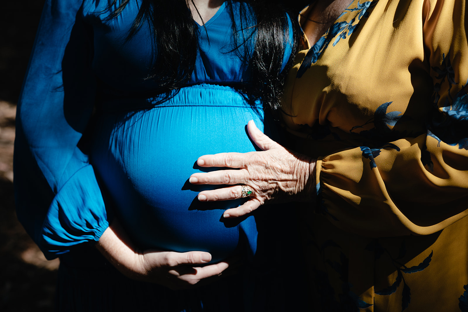 Mother and daughter posing for photos as mother holds her daughters pregnant belly 