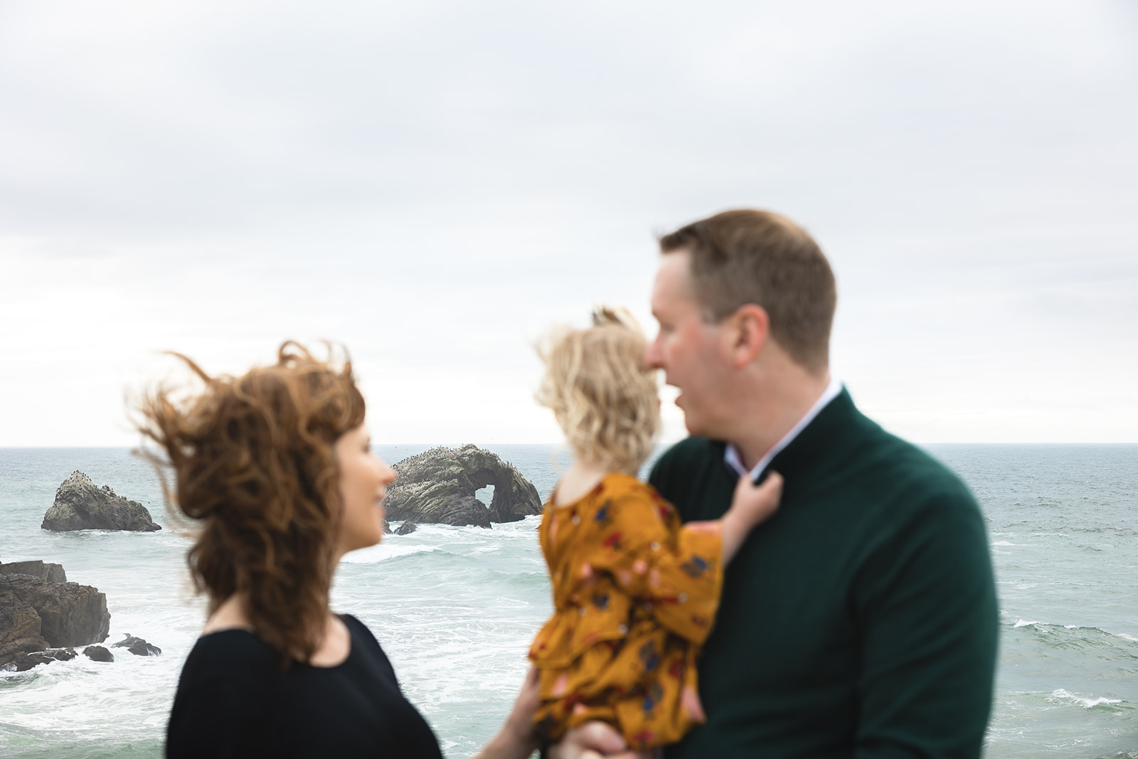 Family of three at Lands End for their family photoshoot with the iconic heart-shaped-rock in the background. 