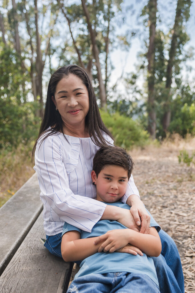 Woman and her son sitting on a bench and smiling at the camera