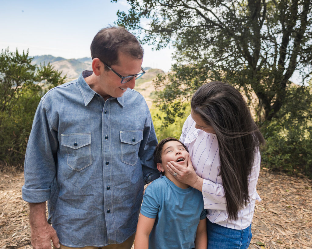 Family of three posing for their Oakland CA family photos with views of Mt. Diablo in the background