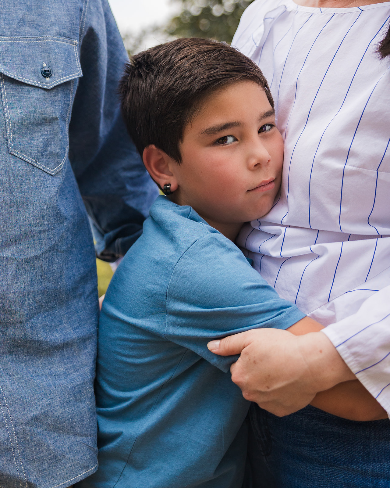 Close up photo of a young boy hugging his mother and father during their outdoor family session