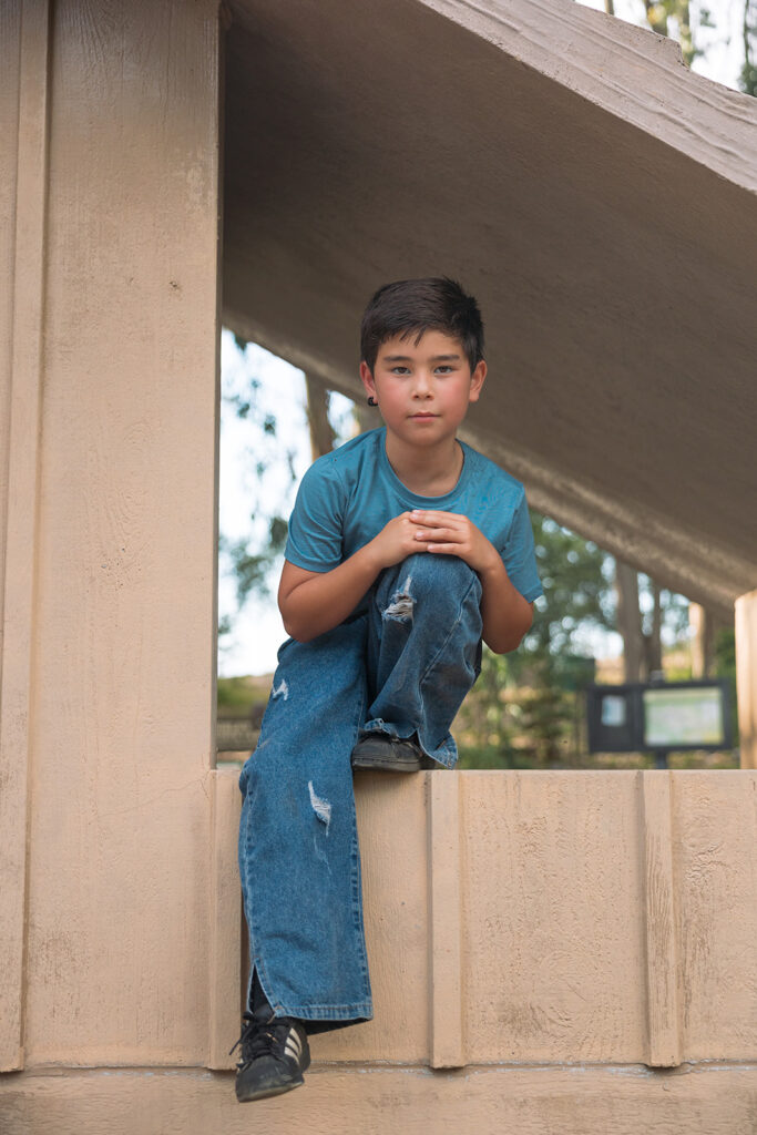 Little boy sitting in a light brown park building structure