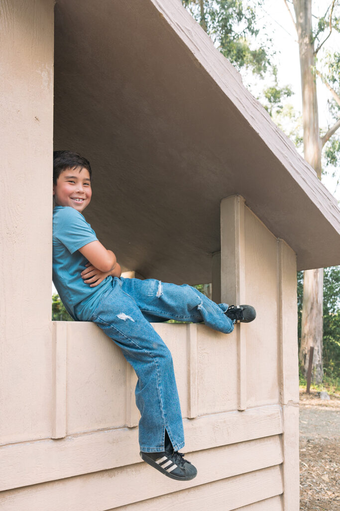 Little boy sitting in a light brown park building structure