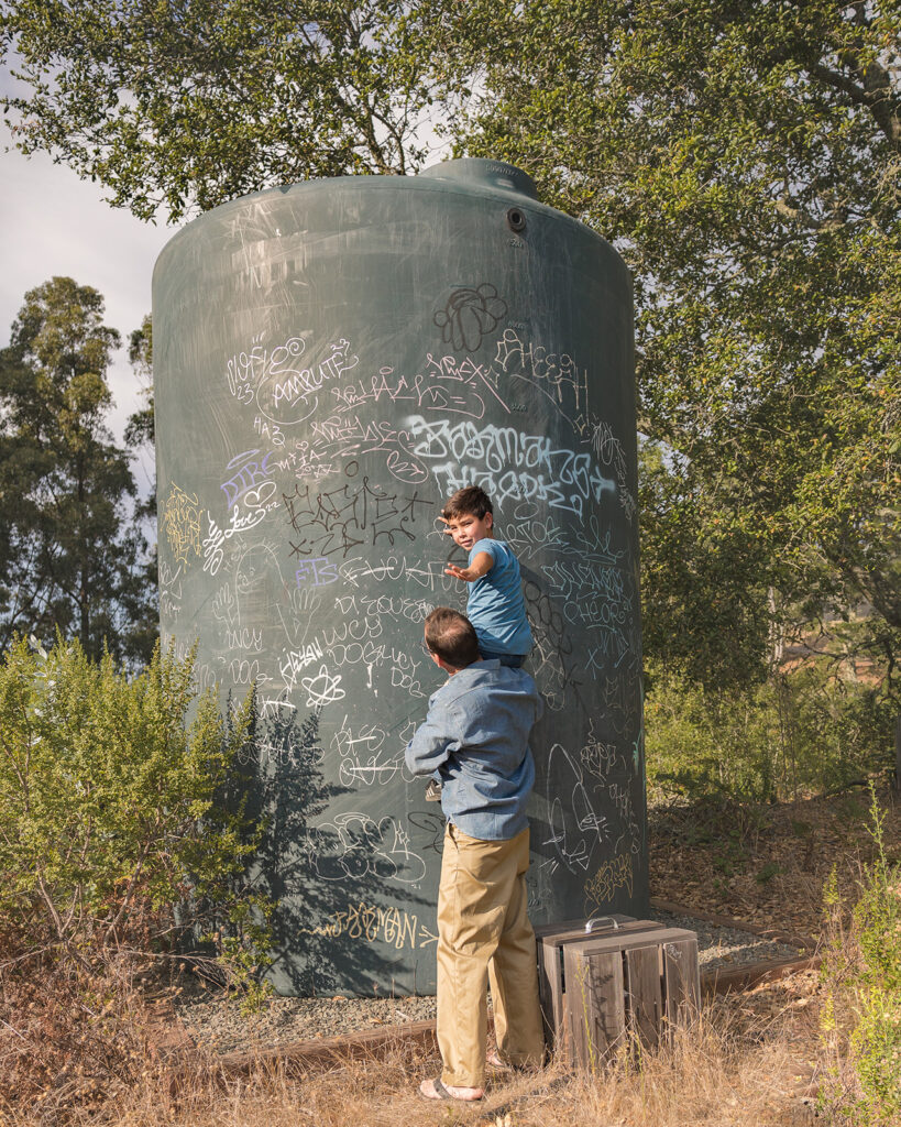 Father holding up his young son to check out graffiti in Sibley Regional Park during their Oakland CA family photos