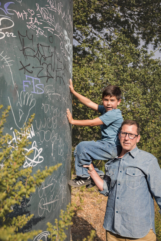 Man holding up his son to check out the graffiti at Sibley Regional Park during their Oakland CA family photos