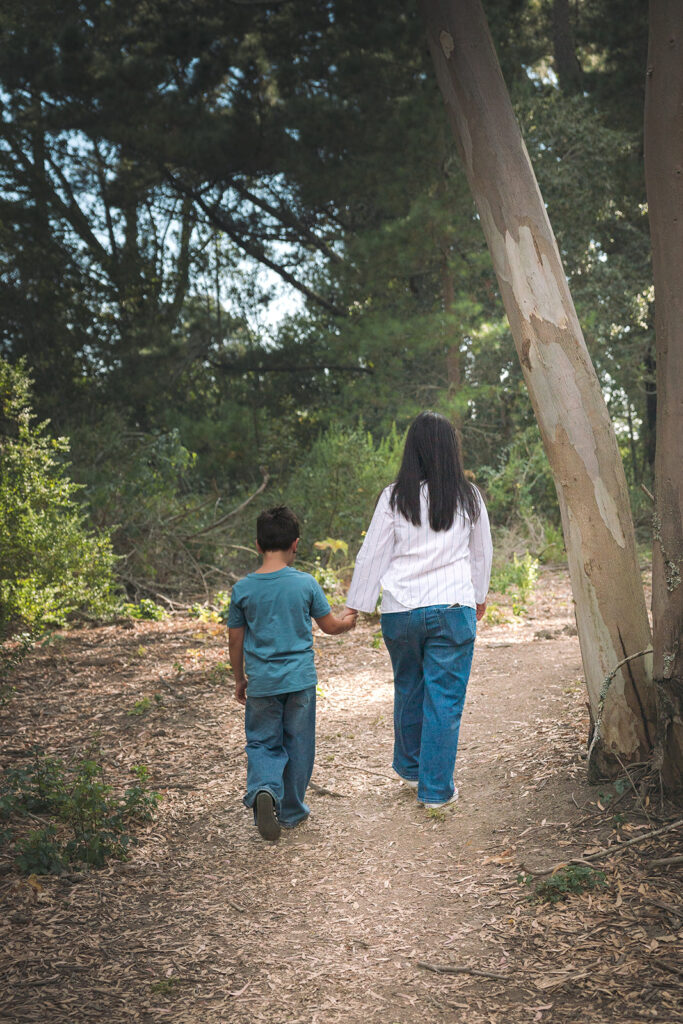 Mother and her son holding hands as they walk away from the camera