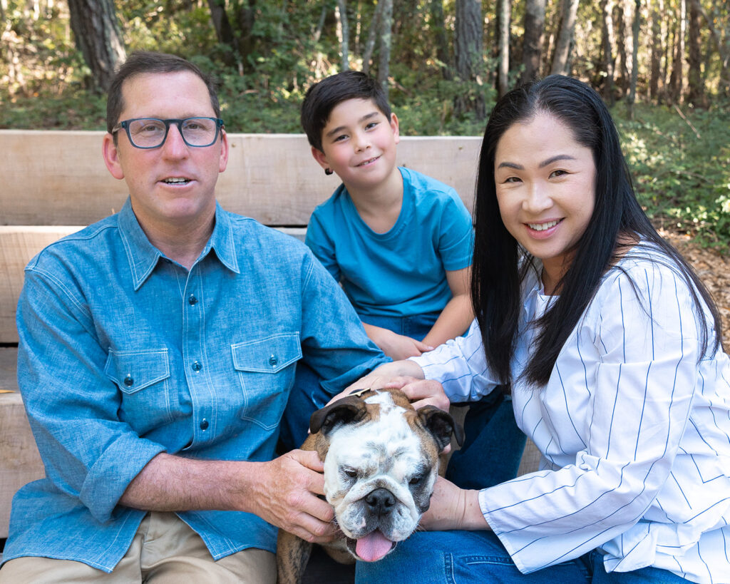 Family of three and their dog sitting on a park bench at Sibley Regional Park for their Oakland CA family photos