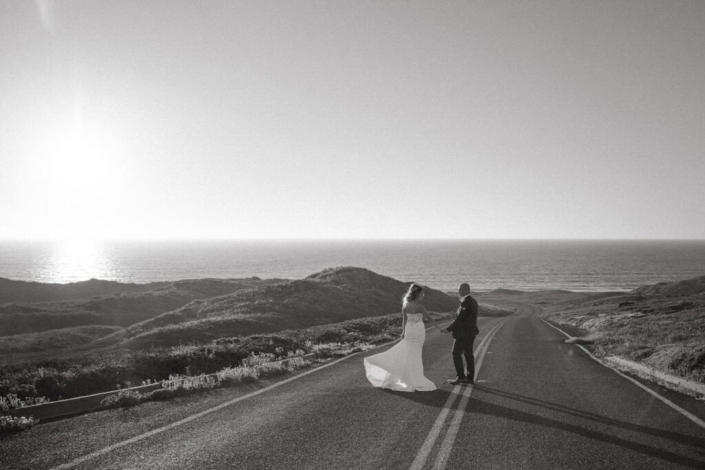 Black and white photo of a couple walking along the road during their intimate Point Reyes elopement in Northern California