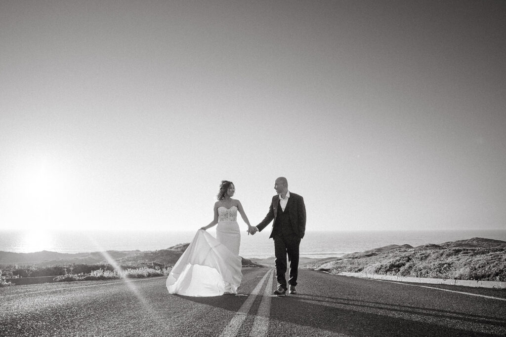 Black and white photo of a couple walking along the road during their intimate Point Reyes elopement in Northern California