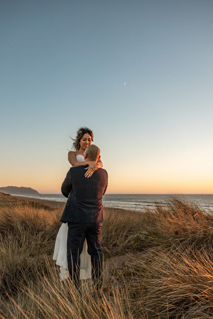 Man holding up his bride during sunset in Point Reyes National Seashore for their intimate Northern California elopement