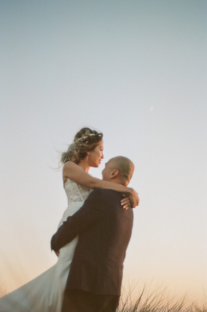 Groom holding up his bride during their intimate Point Reyes elopement in Northern California on 35mm film