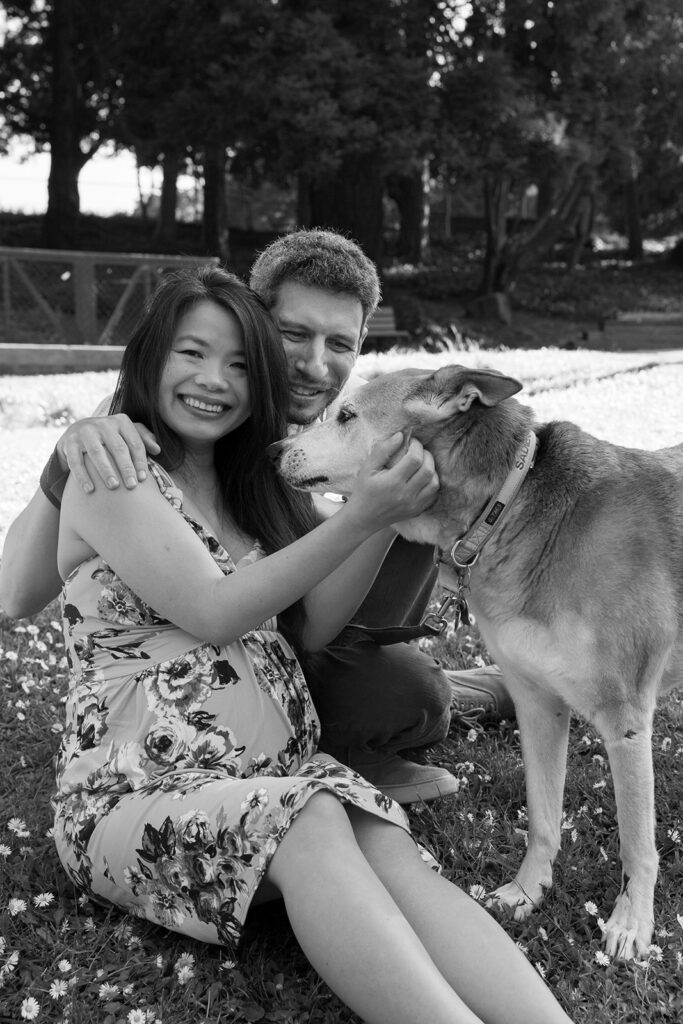 Black and white photo of a man and woman at the park with their dog