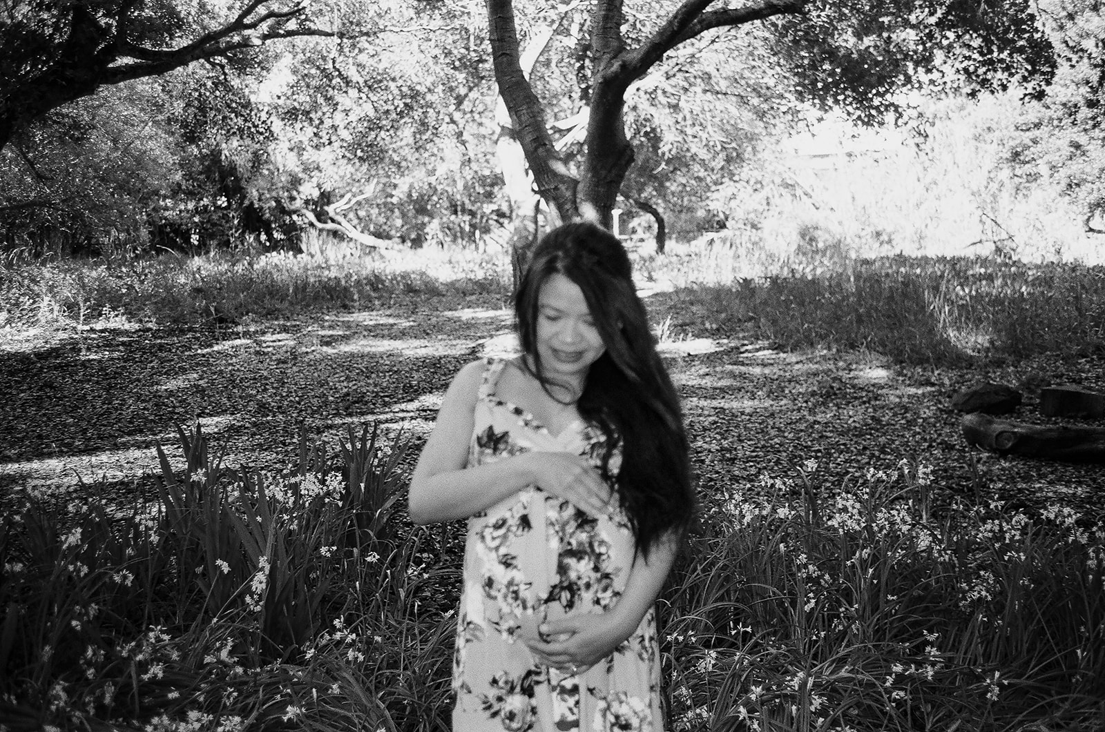 Black and white photo of a pregnant woman holding her belly during her East Bay maternity photography session captured on 35mm film