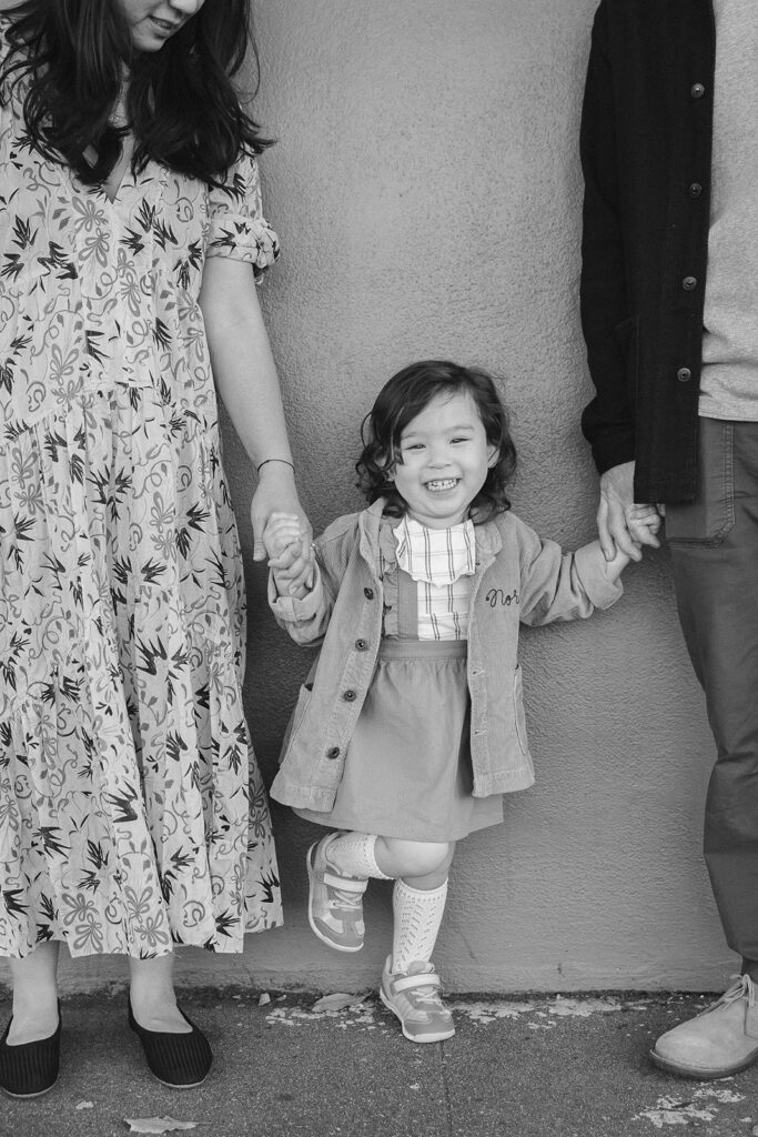 Black and white4 photo of parents holding their young daughters hands