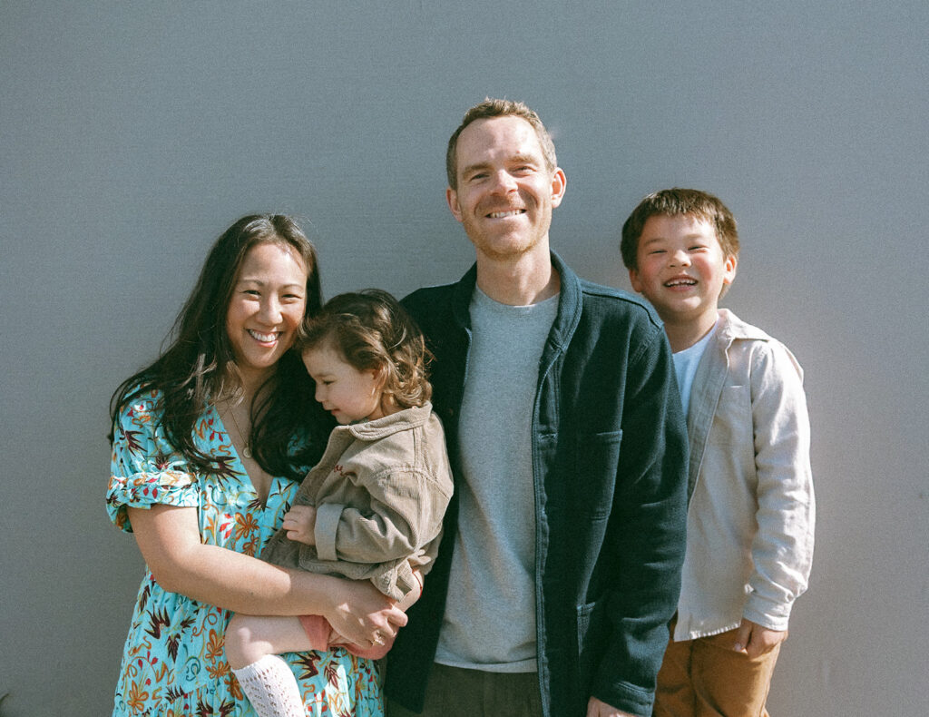 Family of four posing for photos against a grey wall