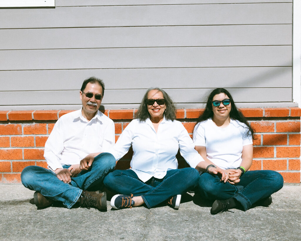 Family of three sitting on the ground and holding hands