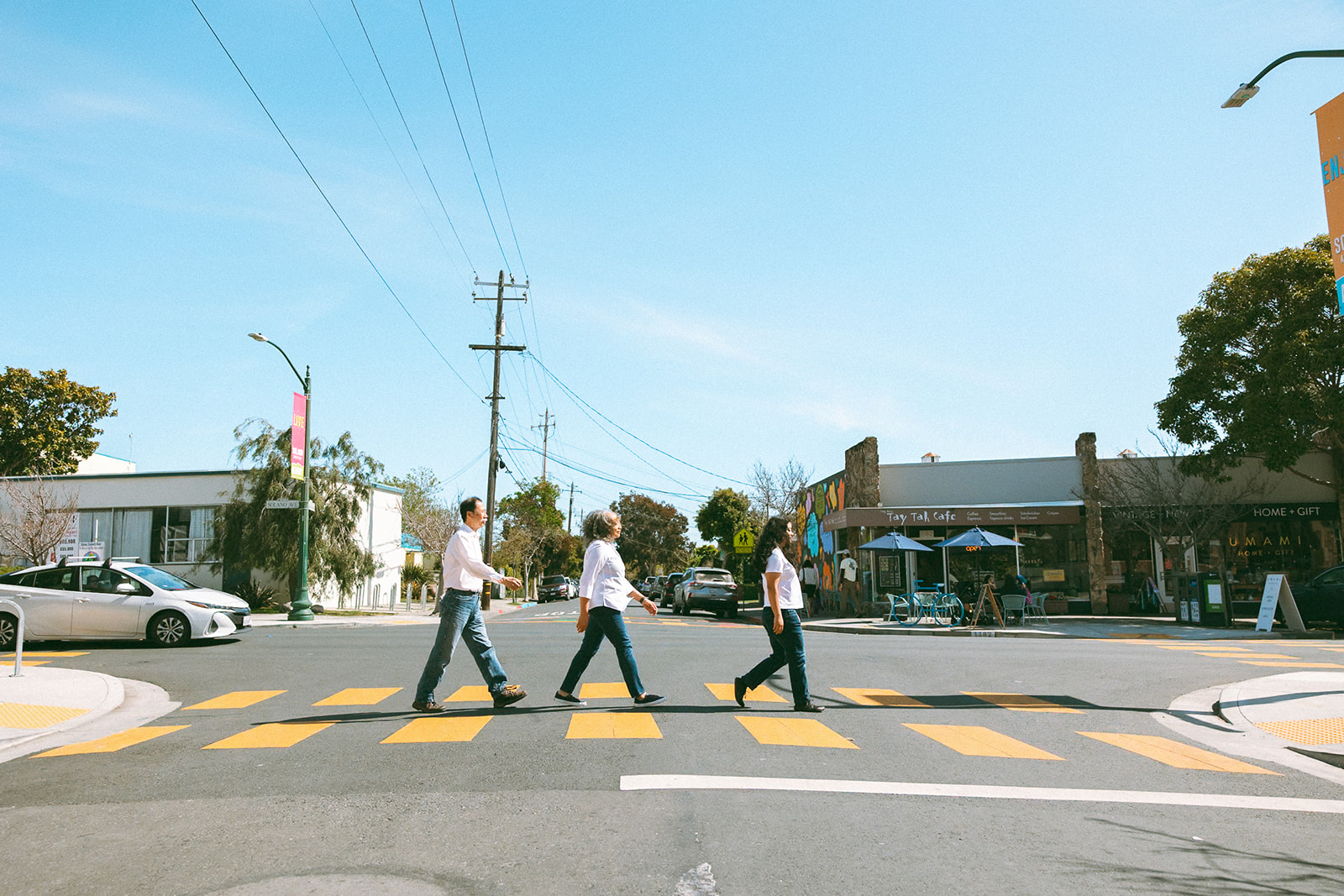 Family of three walking across a crosswalk in the East Bay