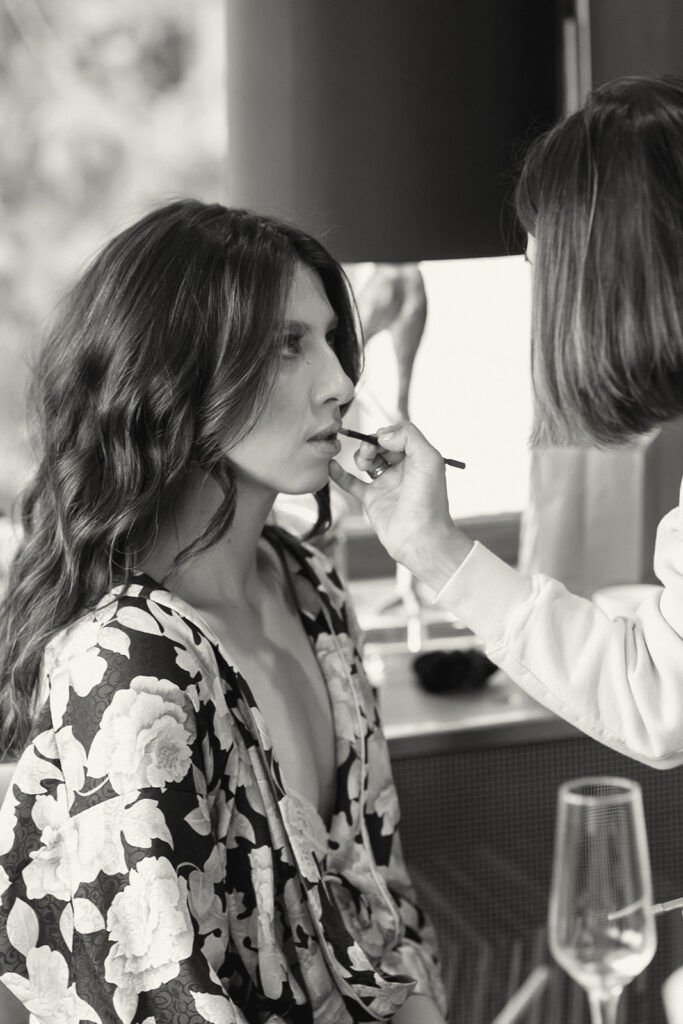 Black and white photo of a bride getting her makeup done