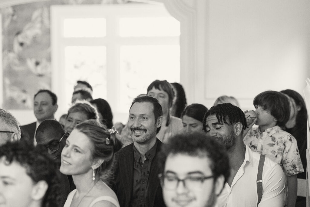 Black and white photo of a wedding guests smiling during the wedding ceremony