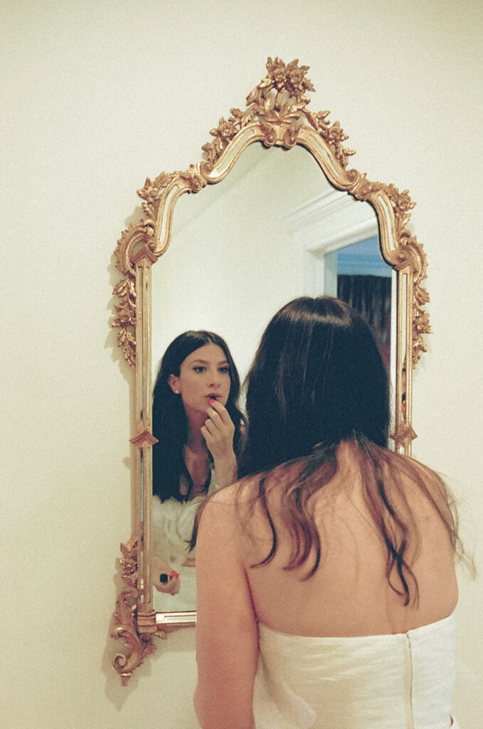 Bride putting lipstick on in the mirror