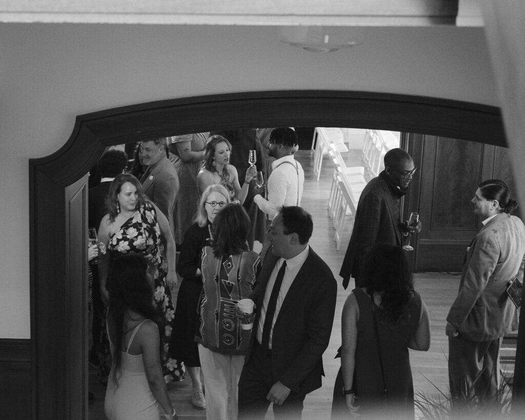 Black and white photo of wedding guests during cocktail hour before the ceremony