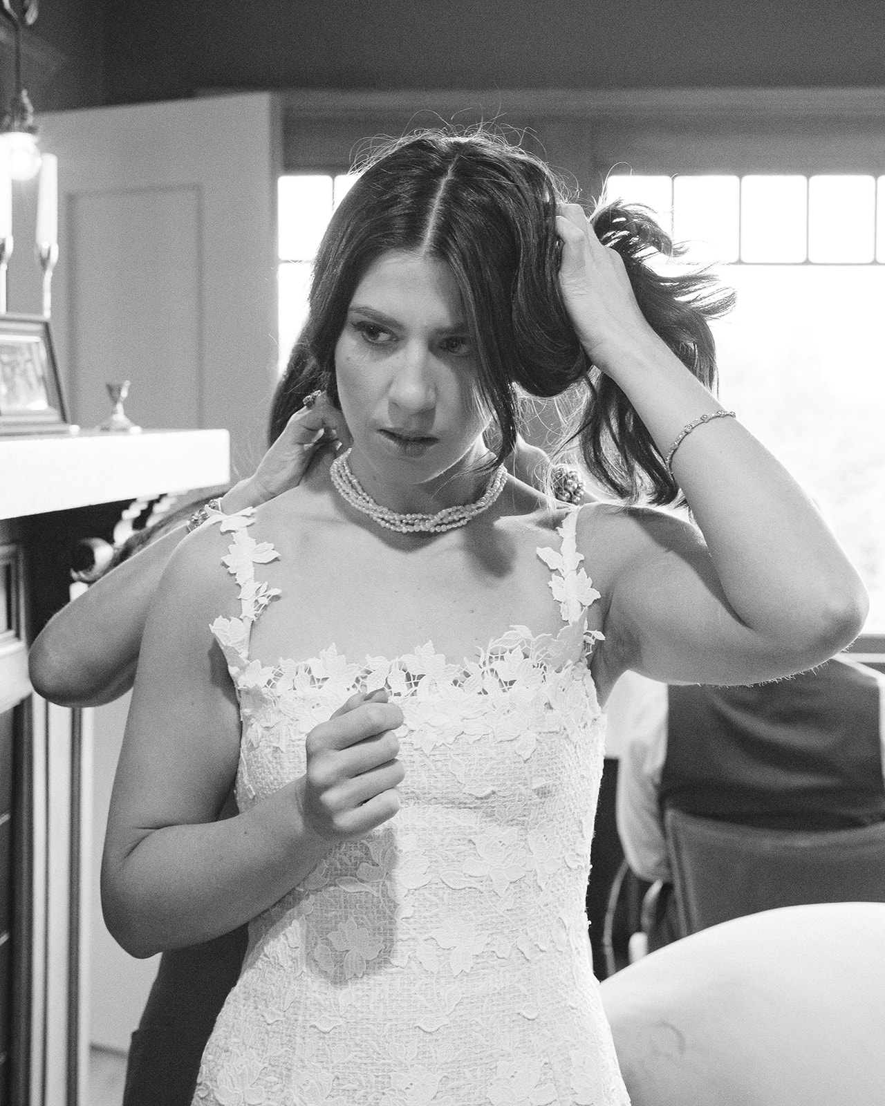 Black and white photo of a bride getting her necklace put on