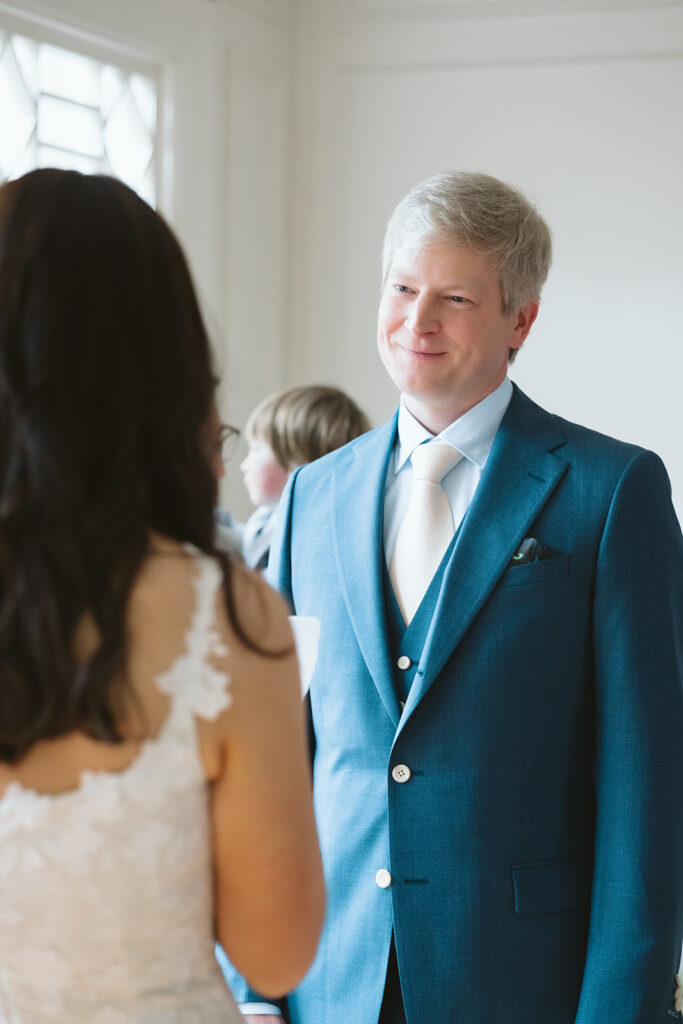 Groom smiling as his bride reads her vows to him during their intimate at-home East Bay wedding ceremony in Berkeley, California