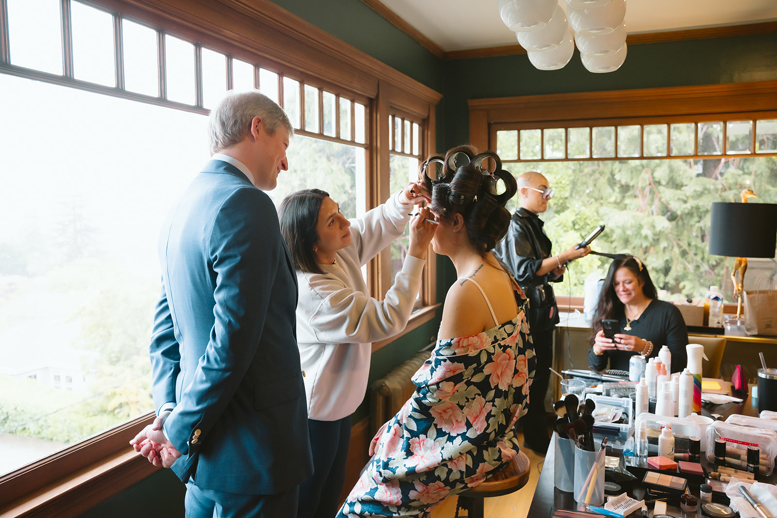 Groom watching his soon to be wife getting her makeup done